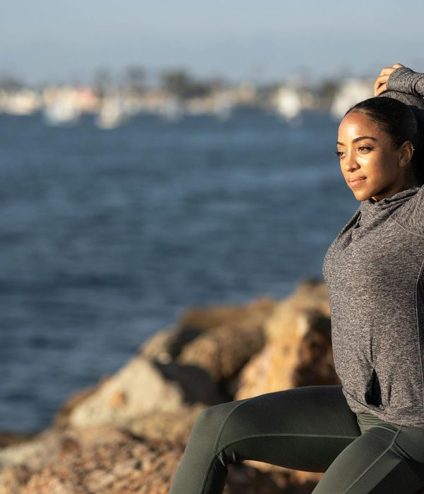 Person stretching outdoors at sunrise, feeling energetic.